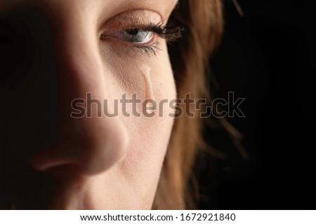 closeup photo of a young woman crying with a tear running down her cheek. Royalty-Free Stock Photo #1672921840