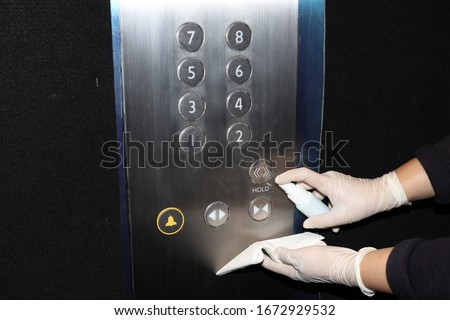 Cleaning staff Cleaned elevator switch button in hospital with alcohol spray and wipe out with clean paper. Corona Virus or bacteria infected protection from touch public object.  Royalty-Free Stock Photo #1672929532