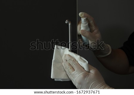 Cleaning staff Cleaned door knob or door holder in office with alcohol spray and wipe out with clean paper. Corona Virus or bacteria infected protection from touch public object.  Royalty-Free Stock Photo #1672937671