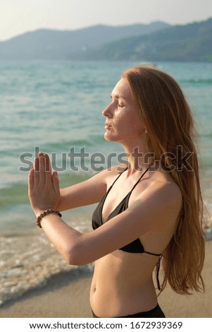 A young woman is practicing yoga on the ocean.