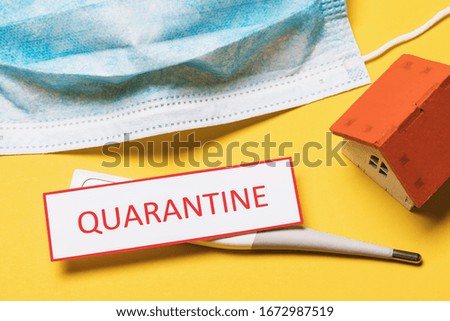 Medical mask, toy house, thermometer and tag with text. Home quarantine concept