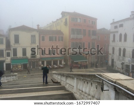 Fog in Venice, building and things dissolving, dreamy landscape, mist, woman walking in the mist