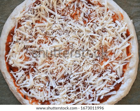 Pizza base with grated cheese. Top view.