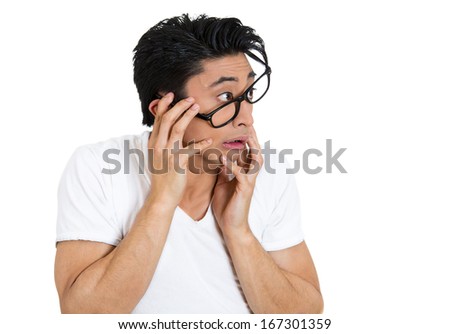 Closeup portrait of nervous, stressed young nerdy guy man in panic and fear, eyeglasses messed up, looking anxiously craving something isolated on white background. Negative emotion expression feeling