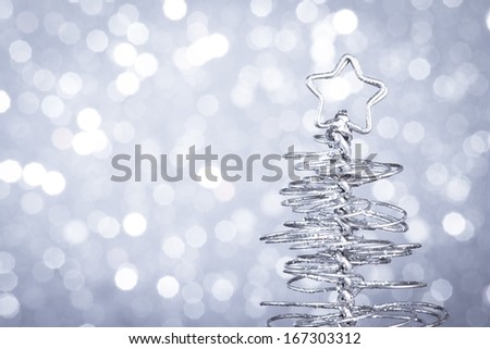 detail of metallic modern christmas tree on wood table on silver tint light bokeh background with space for text