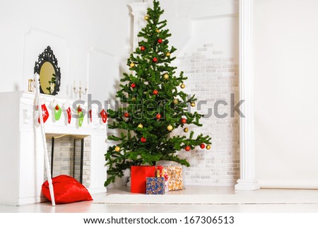 Decorated fir tree and gift boxes near fireplace in living room