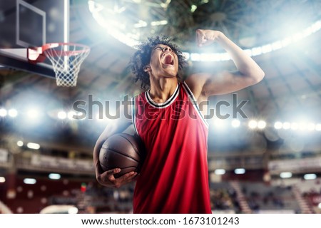 Basketball player wins the match at the basket stadium full of spectators.
