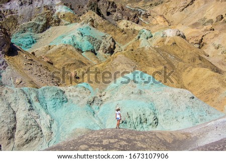 female tourist standing in front of artists palette, colorful hills in death valley national park, united states of america, panoramic picture