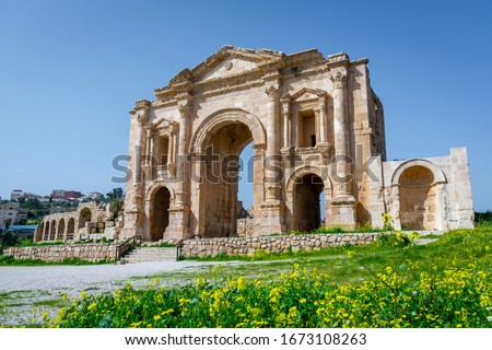 Arch of Hadrian at the roman ruins of Jerash, Jordan. Front view on a sunny day with blue sky. It features some unconventional, possibly Nabataean, architectural features, such as acanthus bases. Royalty-Free Stock Photo #1673108263