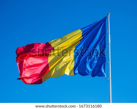Romanian flag in the wind with a blue sky in the background.