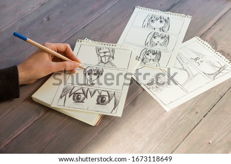 Artist drawing an anime comic book in a studio. Wooden desk, natural light