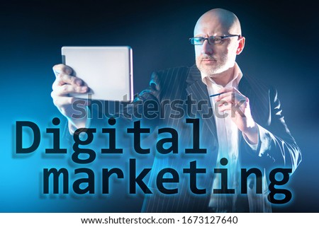 A man with a tablet and stylus in his hands on the background of the inscription Digital marketing. Promotion of goods and services using digital technologies. Internet marketing.