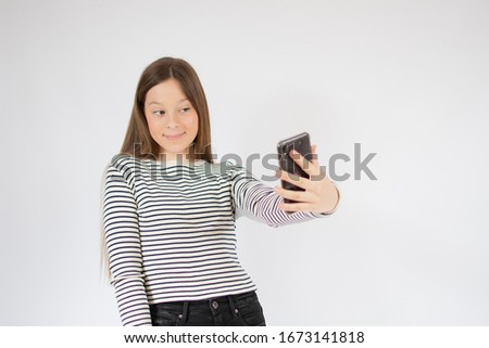 Girl with striped shirt taking a picture with her phone