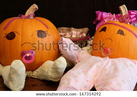 Two pumpkins dressed up as princess babies with pacifiers.