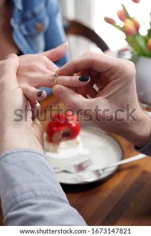 Engagement. The man puts an engagement ring on the woman's finger.