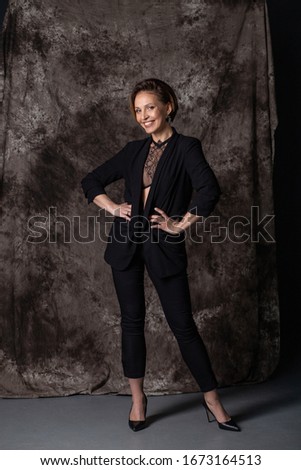 young woman in black trouser suit standing smiling in winner pose