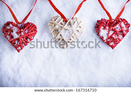 Three  beautiful romantic vintage hearts are hanging on a red band on a white snow background. Love and St. Valentines Day concept. 
