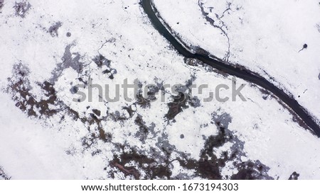 Wetlands with a small river covered by snow. Many footprints of wild animals, Aerial View  