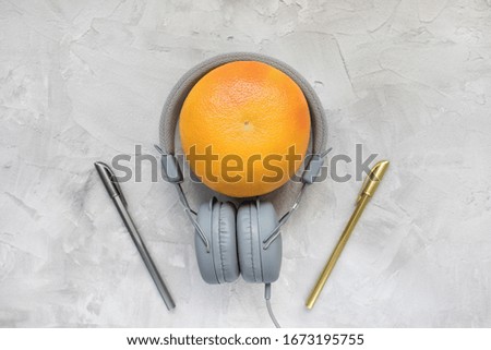 Grapefruit, headphones and pens on gray background. Nutrition and food podcast concept. Top view, flat lay, copy space