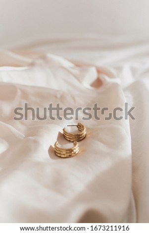 golden jewels: Rings, bracelet, earrings and necklace on warm color fabric background 