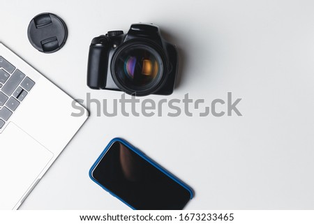 Photographer's workplace on a white background. Modern laptop, digital camera, lens, battery, smartphone. Minimalism. Top view. Copy space. Equipment for the photographer. The concept of freelancing