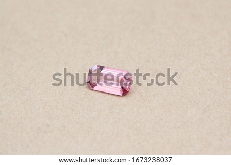 Gemstone Pink Sapphire Tourmaline emerald cut shape on brown craft paper background with selective focus