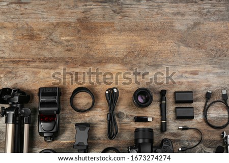 Flat lay composition with camera and video production equipment on wooden table. Space for text