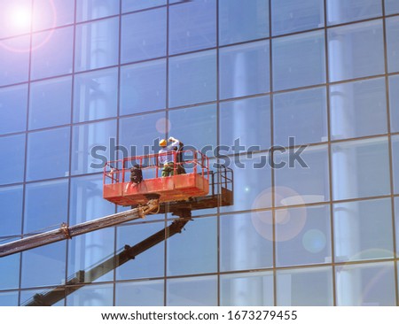 Working window cleaner on a telescopic platform washes the Windows of a modern skyscraper, work with high risk Royalty-Free Stock Photo #1673279455