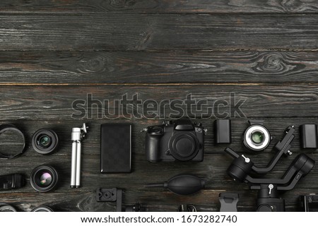 Flat lay composition with camera and video production equipment on black wooden table. Space for text