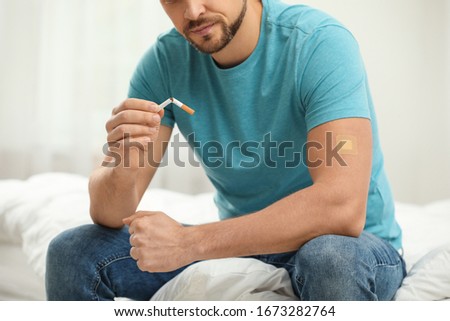 Man with nicotine patch and cigarette in bedroom, closeup Royalty-Free Stock Photo #1673282764
