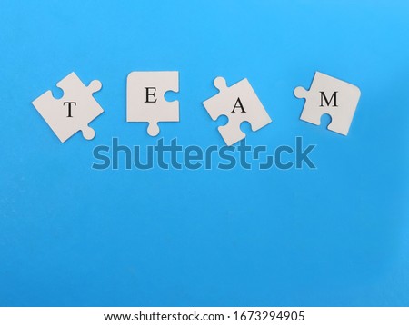 Words "TEAM" on white jigsaw puzzle pieces with blue background,Business concept. 