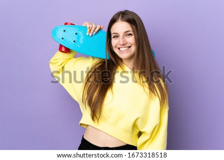 Young caucasian woman isolated on purple background with a skate