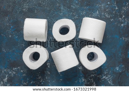 Toilet paper rolls on dark blue background. Top view, copy space
