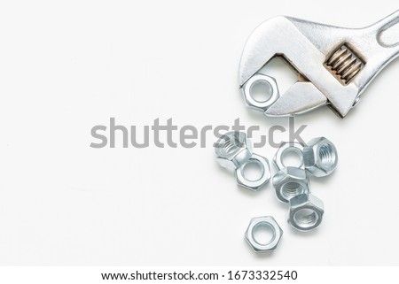 Adjustable wrench and nuts on white flat lay background with copy space.