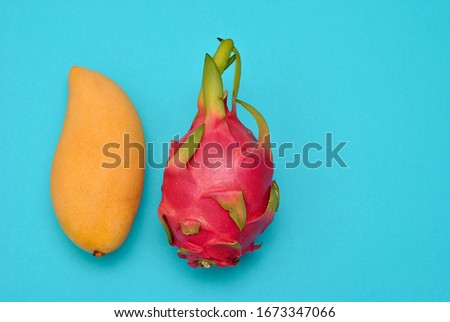 Mango and dragon fruit pitahaya beautiful picture on the blue background. Top view minimalistic beauty fruits concept. Dietology and vitamin food, vegetarian delicious meals