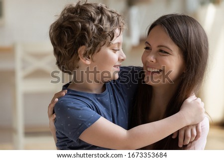 Close up of happy young mother hold in arms look in eyes cuddle cute little son, smiling mom hug embrace small preschooler boy child enjoying weekend spending leisure family time together
