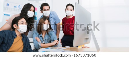 asian small business startup multiracial brainstorm meeting with laptop and chart paper everyone mask for covid19 protection corona flu prevent healty ideas concept office background Royalty-Free Stock Photo #1673371060