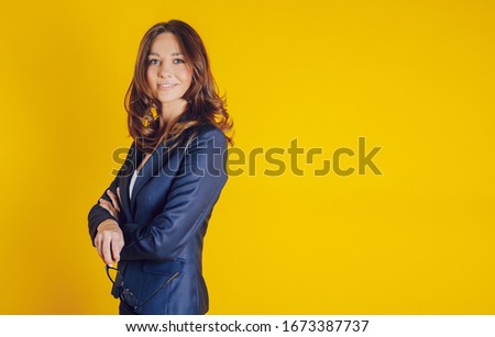A beautiful young woman elegantly dressed as a teacher, like a bissnes lady, smiling and well placed on a yellow background, with her eyes turned to a clear space for text writing or image placement