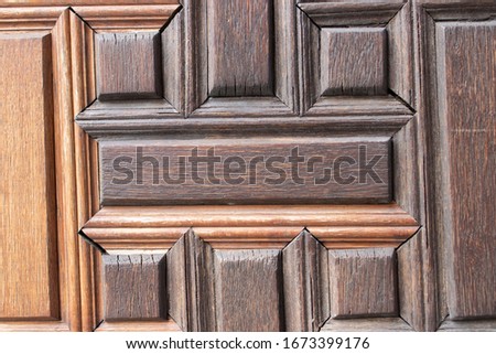 Old wooden door with geometric pattern. Wooden surface is tinted in warm color. Autumn background, copy space.