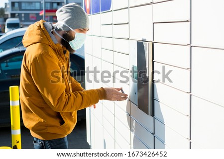 Man i a mask getting package from mailbox during coronavirus Royalty-Free Stock Photo #1673426452