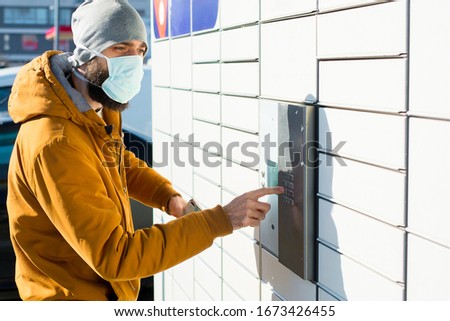 Man i a mask getting package from mailbox during coronavirus Royalty-Free Stock Photo #1673426455