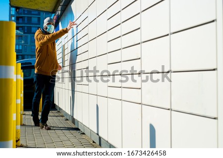Man i a mask getting package from mailbox during coronavirus Royalty-Free Stock Photo #1673426458