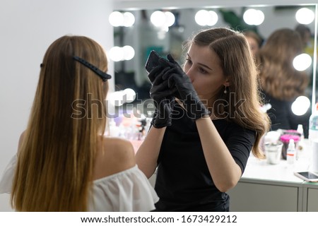 Young beautician caucasian girl holds model eyebrow correction Beautician at work is the workplace of an eyebrow specialist. Shutting result on phone Take a picture Beauty industry. Lifestyle