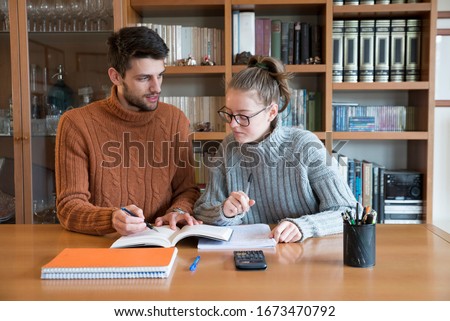 Teacher giving private lessons to a student in a library. Improving through tutoring.  Royalty-Free Stock Photo #1673470792