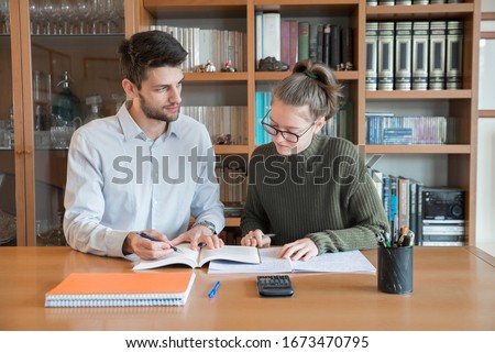 Teacher giving private lessons to a student in a library. Improving through tutoring.  Royalty-Free Stock Photo #1673470795