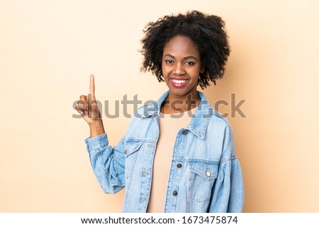 Young African American woman isolated on beige background showing and lifting a finger in sign of the best