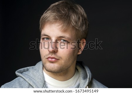 Attractive male portrait photo. Black background. Young man in a casual sweatshirt. Gray eyes. 
