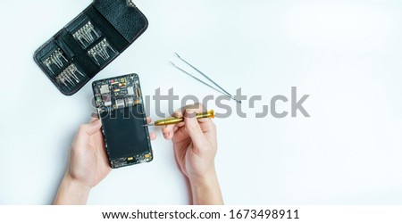 Smartphone repair. Dismantled the smartphone, screwdrivers for disassembling the phone. Flat lay, top view. White background. Space for text. Banner.