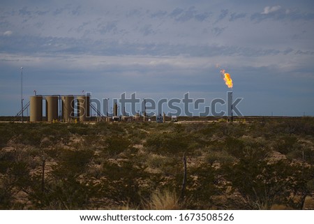 Permian Basin Gas Flare - Burning excess natural gas at a crude oil storage site is a common practice when gas prices deem it uneconomical to transport the gas to market. Royalty-Free Stock Photo #1673508526