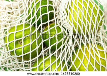 Reusable bag and green fruits on green background. Monochrome. Zero waste